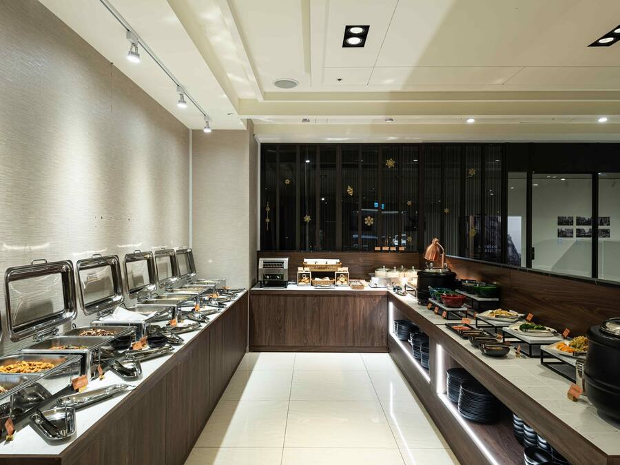 A buffet with multiple food stations, a coffee bar, and a counter with a coffee machine.