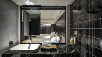 Een moderne badkamer met een grote spiegel, een witte wasbak en een wand betegeld met zwarte tegels.