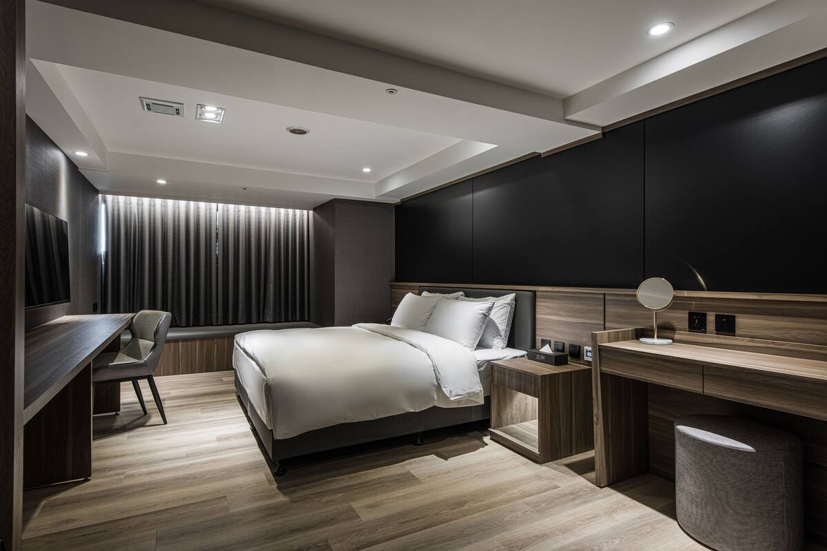 A modern bedroom with a bed, desk, chair, and built-in wardrobe.