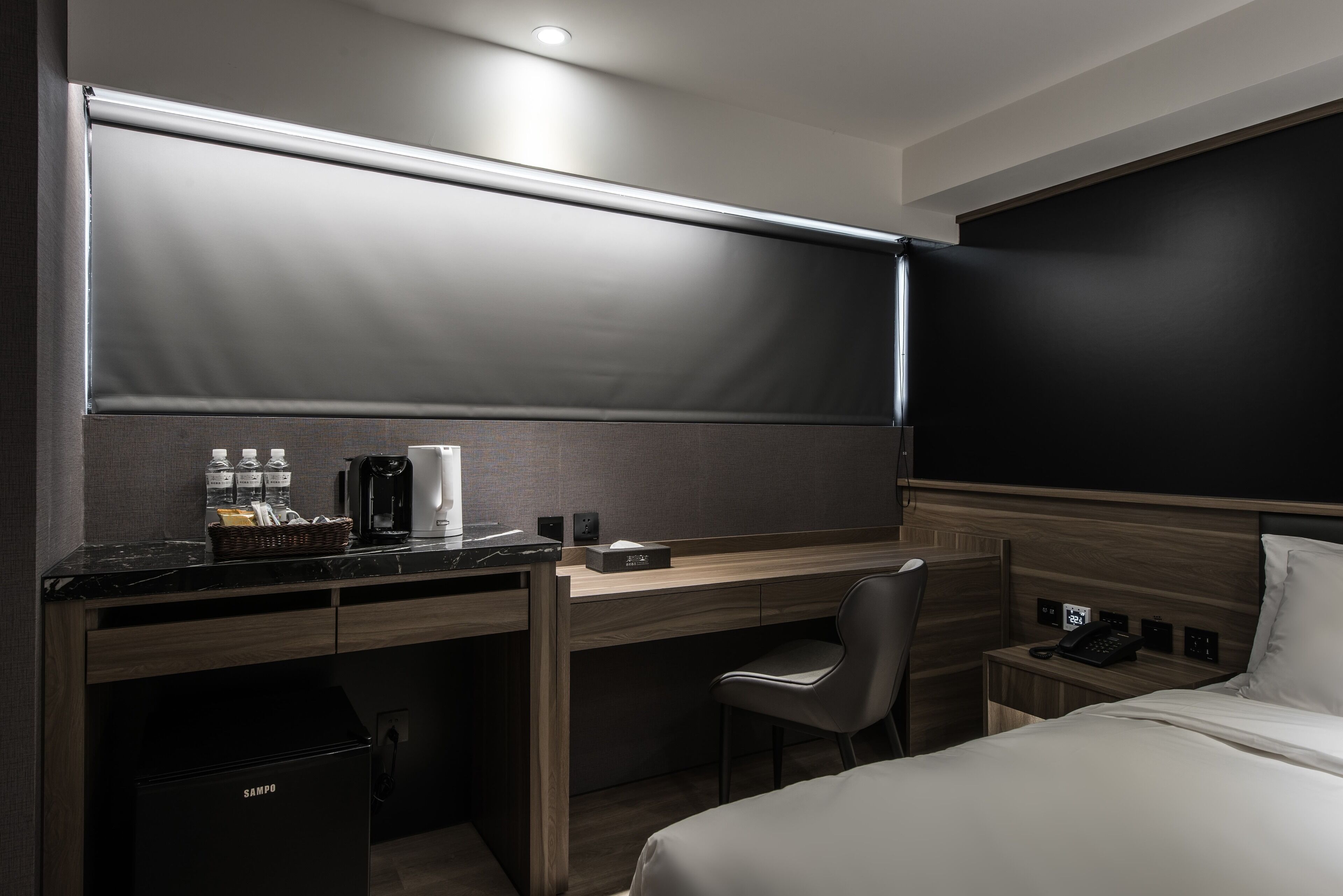 A modern hotel room with a desk, chair, and bed.