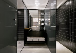A modern bathroom with a black tiled wall, a white sink, and a mirror. - Autumn Willow Hotel (Taichung)