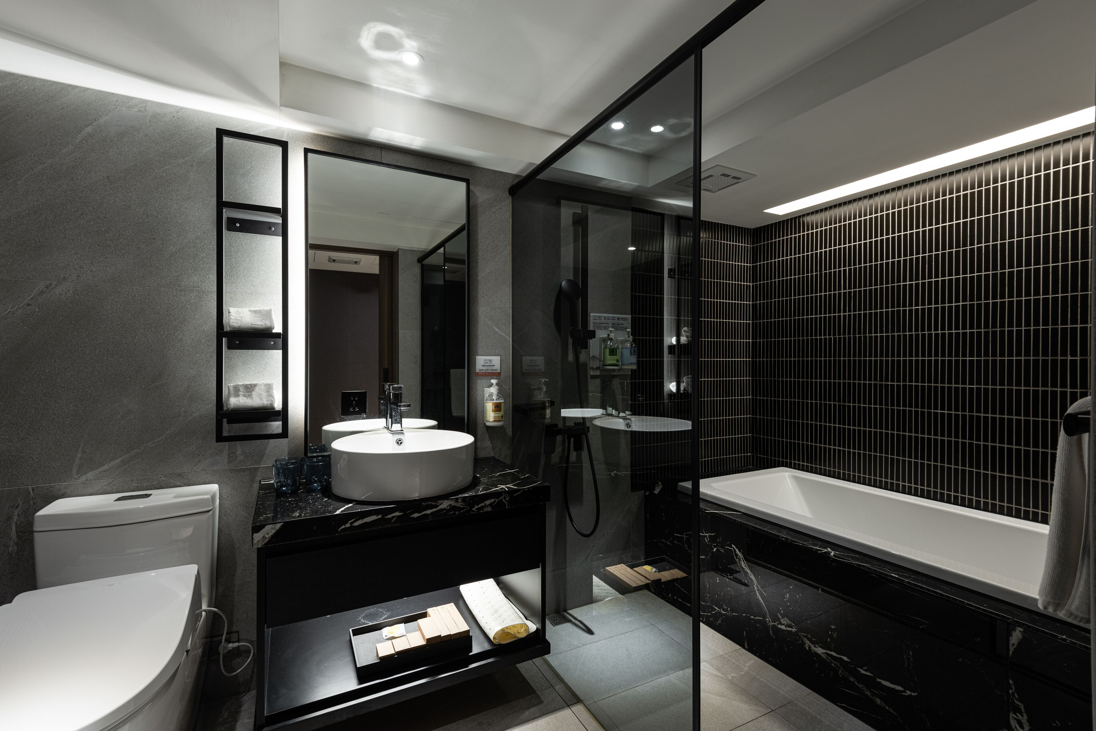 A modern bathroom with a toilet, a sink, a mirror, and a bathtub.