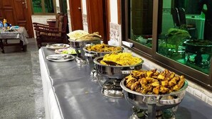 A buffet table with various dishes, including rice and meat, in a dining area with wooden chairs and a window. - C4 Mirpur City AJK Overseas Pakistanis Villa 3bed Guesthouse (Mirpur city AJK)