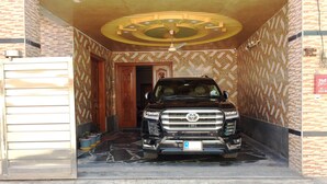 A black SUV parked inside a building with patterned walls and a ceiling fan. - C4 Mirpur City AJK Overseas Pakistanis Villa 3bed Guesthouse (Mirpur city AJK)