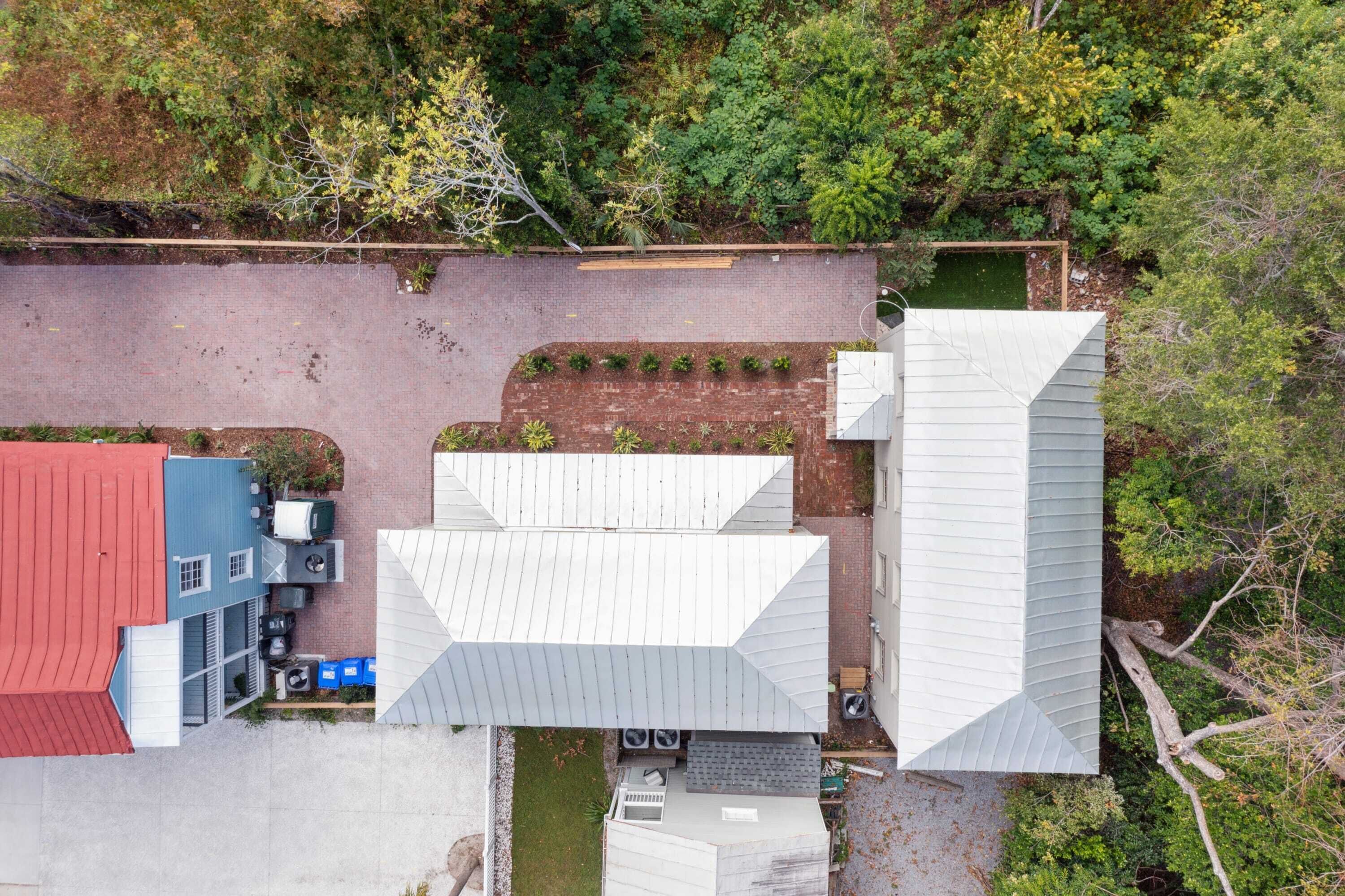 An aerial view of a building complex with multiple structures, including a tall white building, a shorter red-roofed building, and a blue building with a sloped roof.