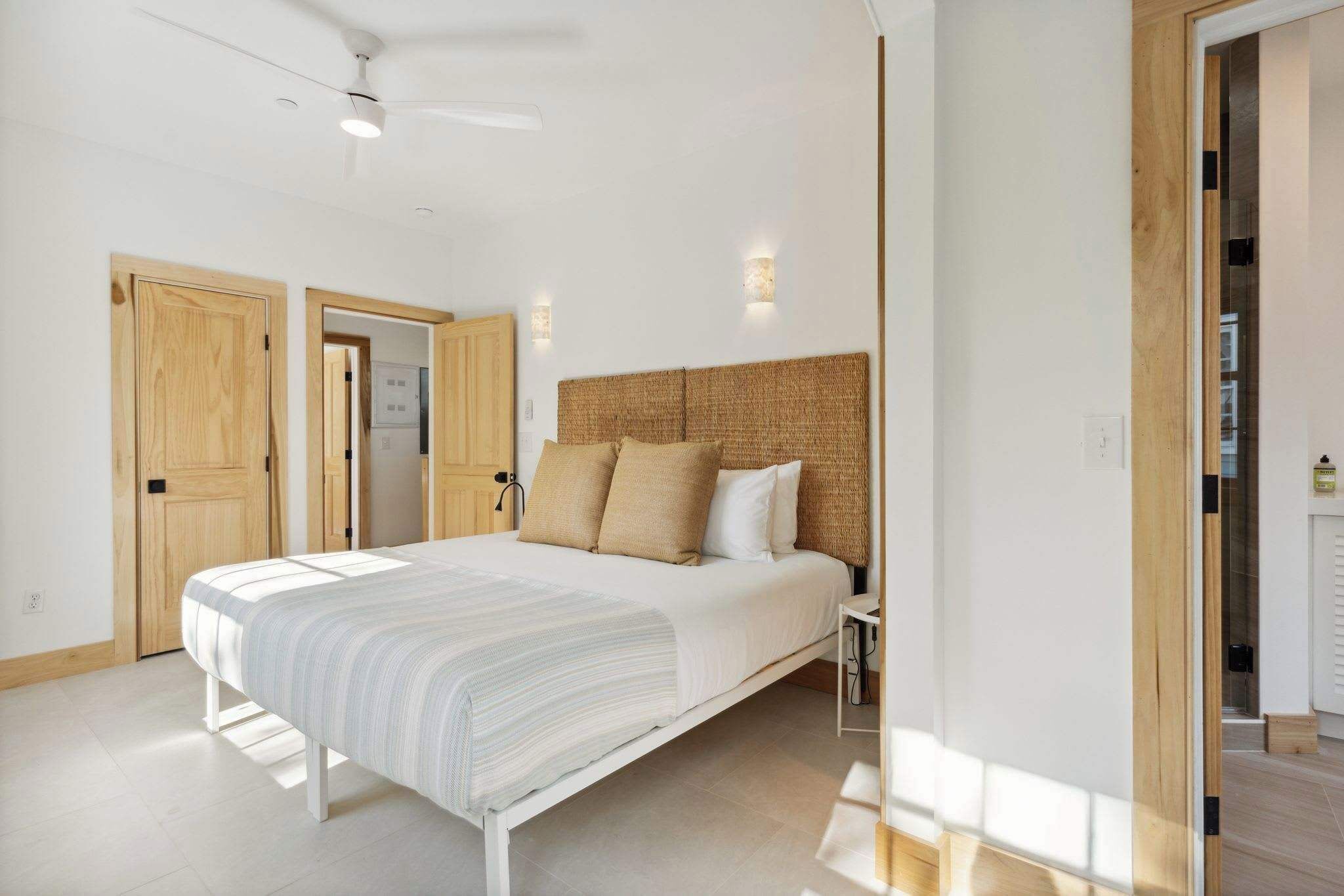 A bedroom with a bed, wooden doors, and a ceiling fan.