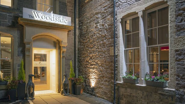 Een stenen gebouw met een bord waarop "The Woodside" staat.