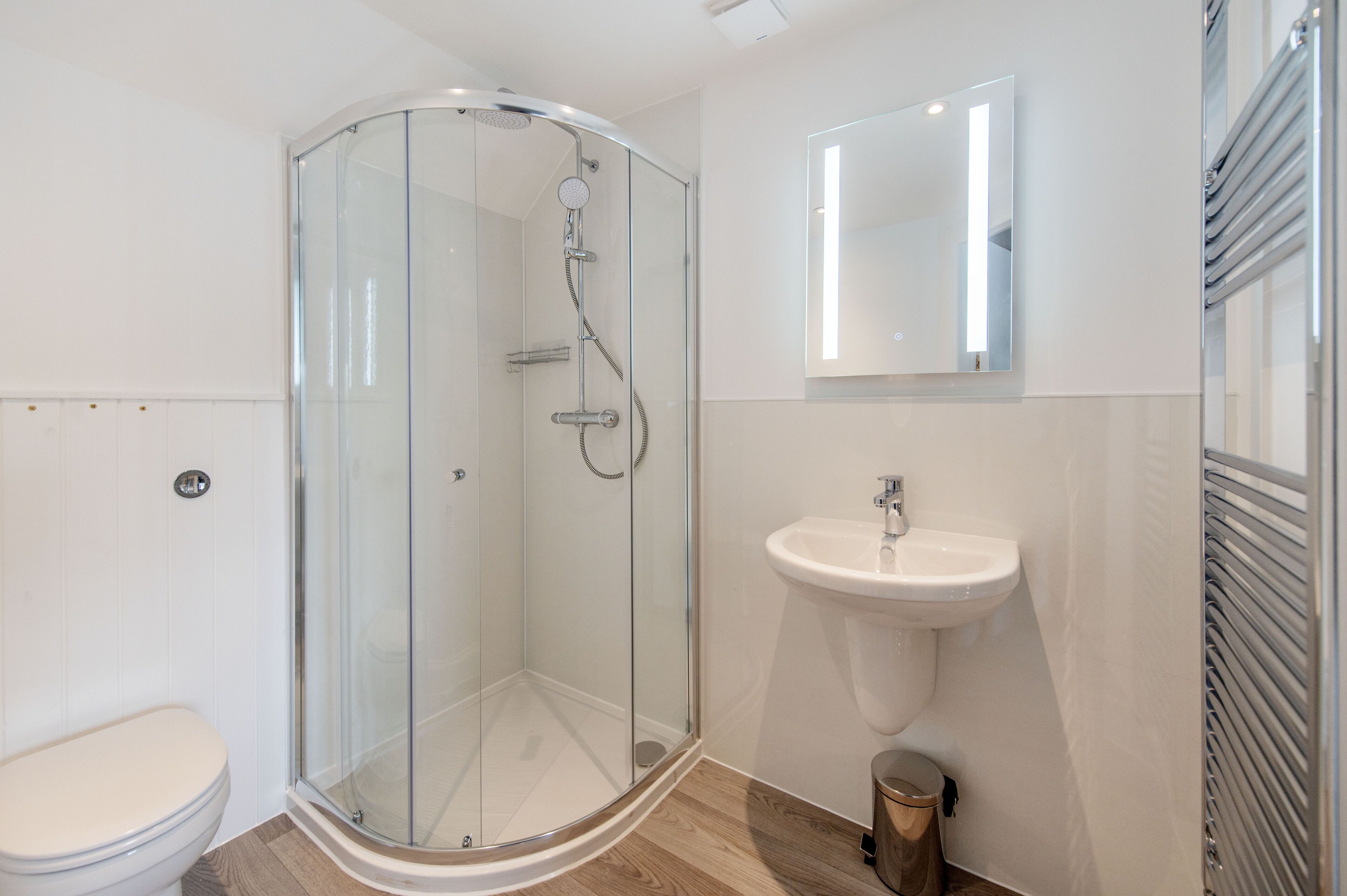 A modern bathroom with a glass-enclosed shower, a white sink, and a toilet.