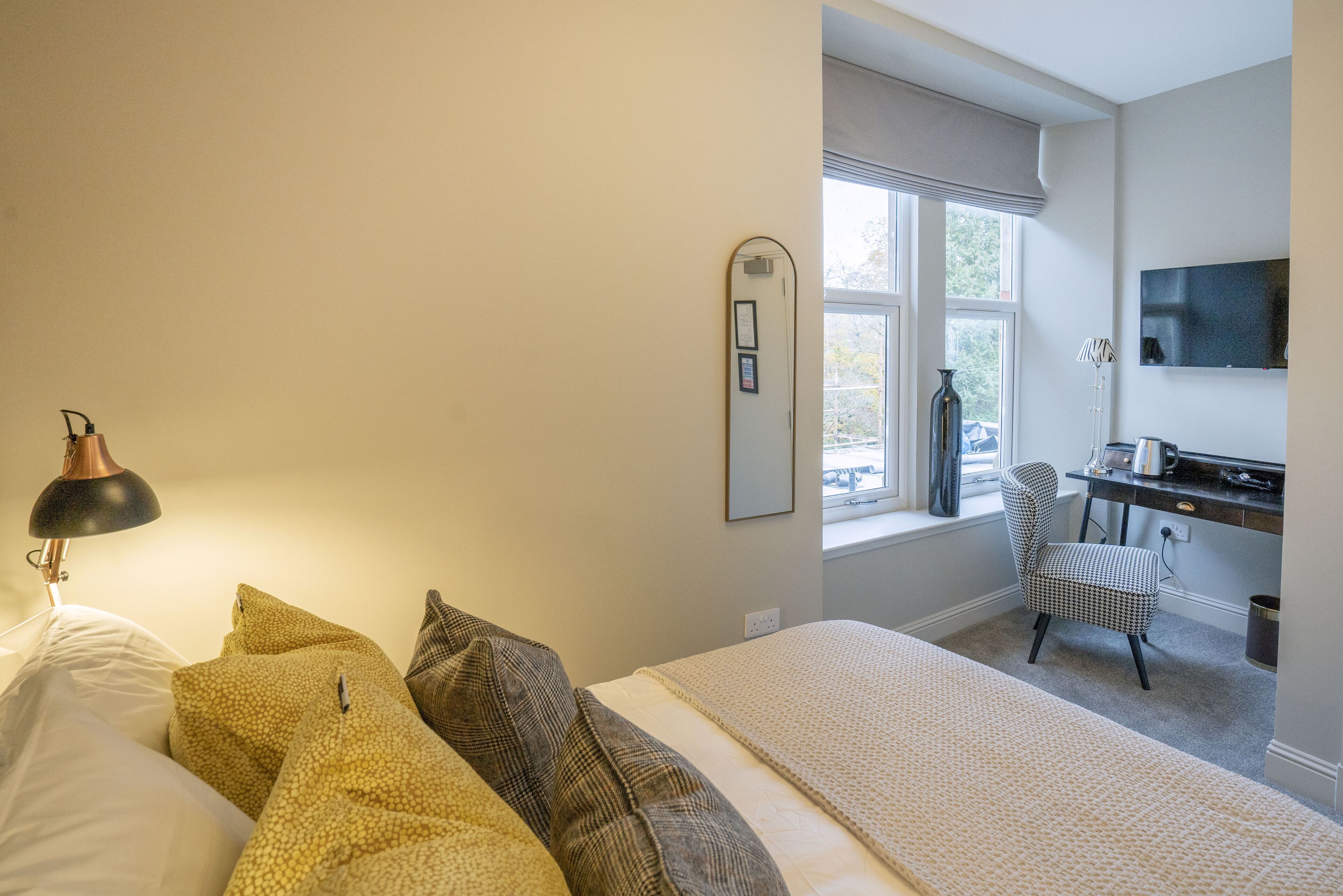 Ein Schlafzimmer mit Bett, Kissen, Schreibtisch, Stuhl und Fenster.