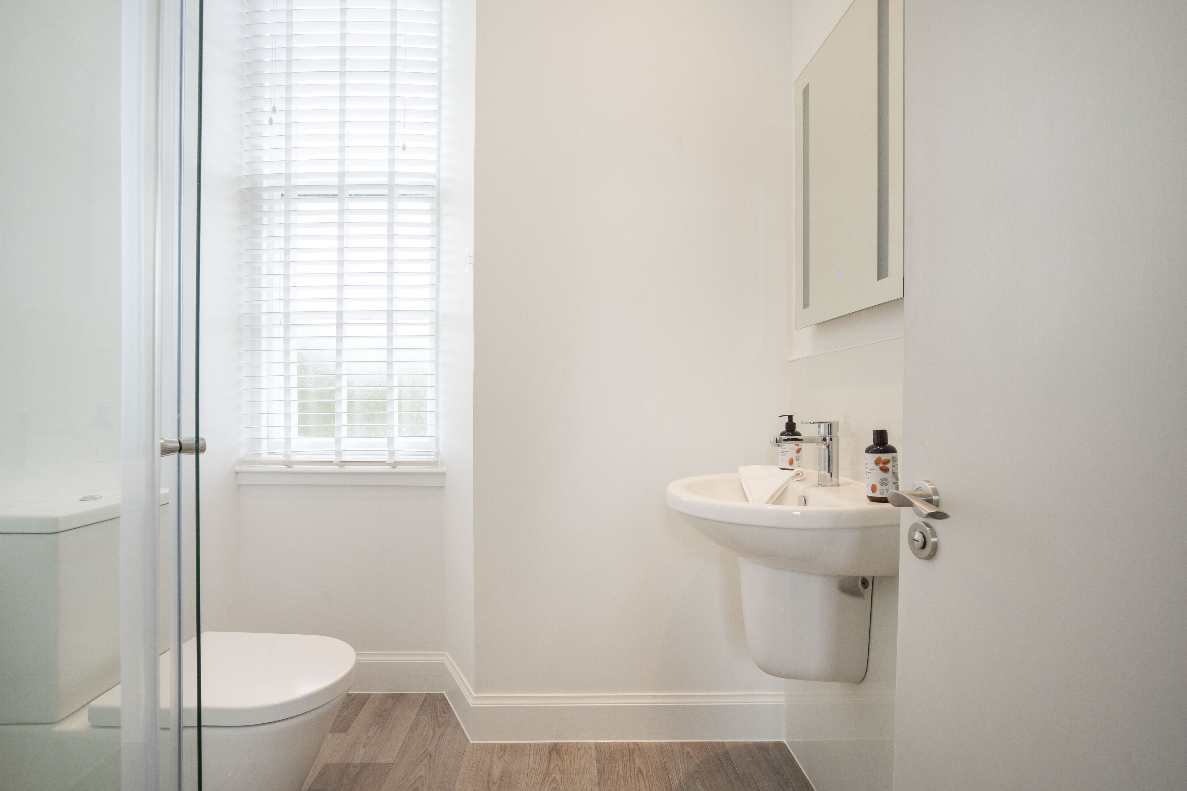 Een badkamer met toilet, wastafel en een raam met zonwering.