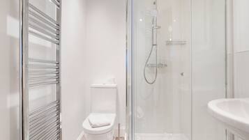 Un baño moderno con cabina de ducha de vidrio, inodoro y lavamanos.