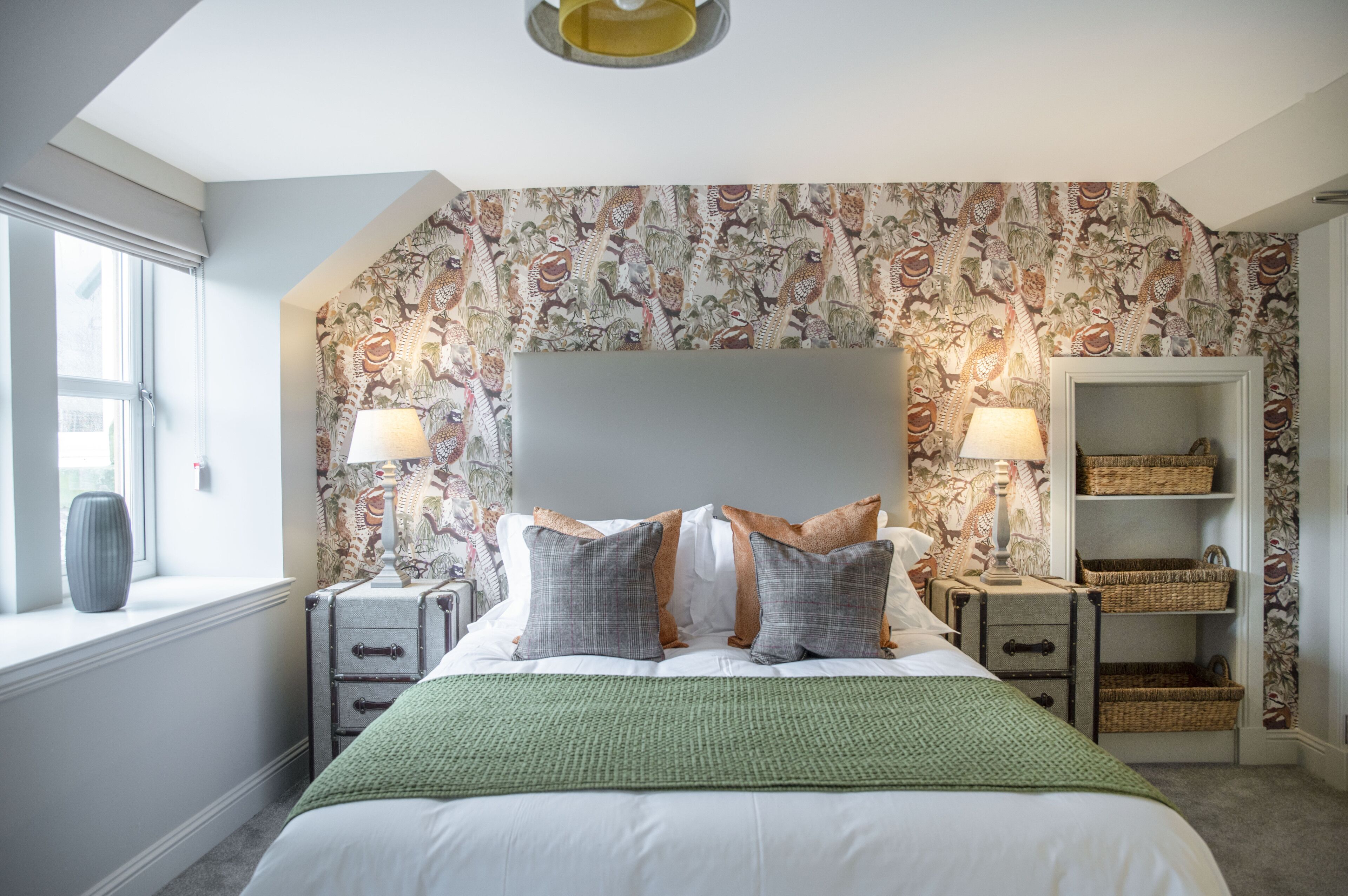 Une chambre à coucher avec un grand lit, deux tables de chevet, une tête de lit et une fenêtre.