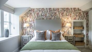 A bedroom with a large bed, two nightstands, a headboard, and a window.