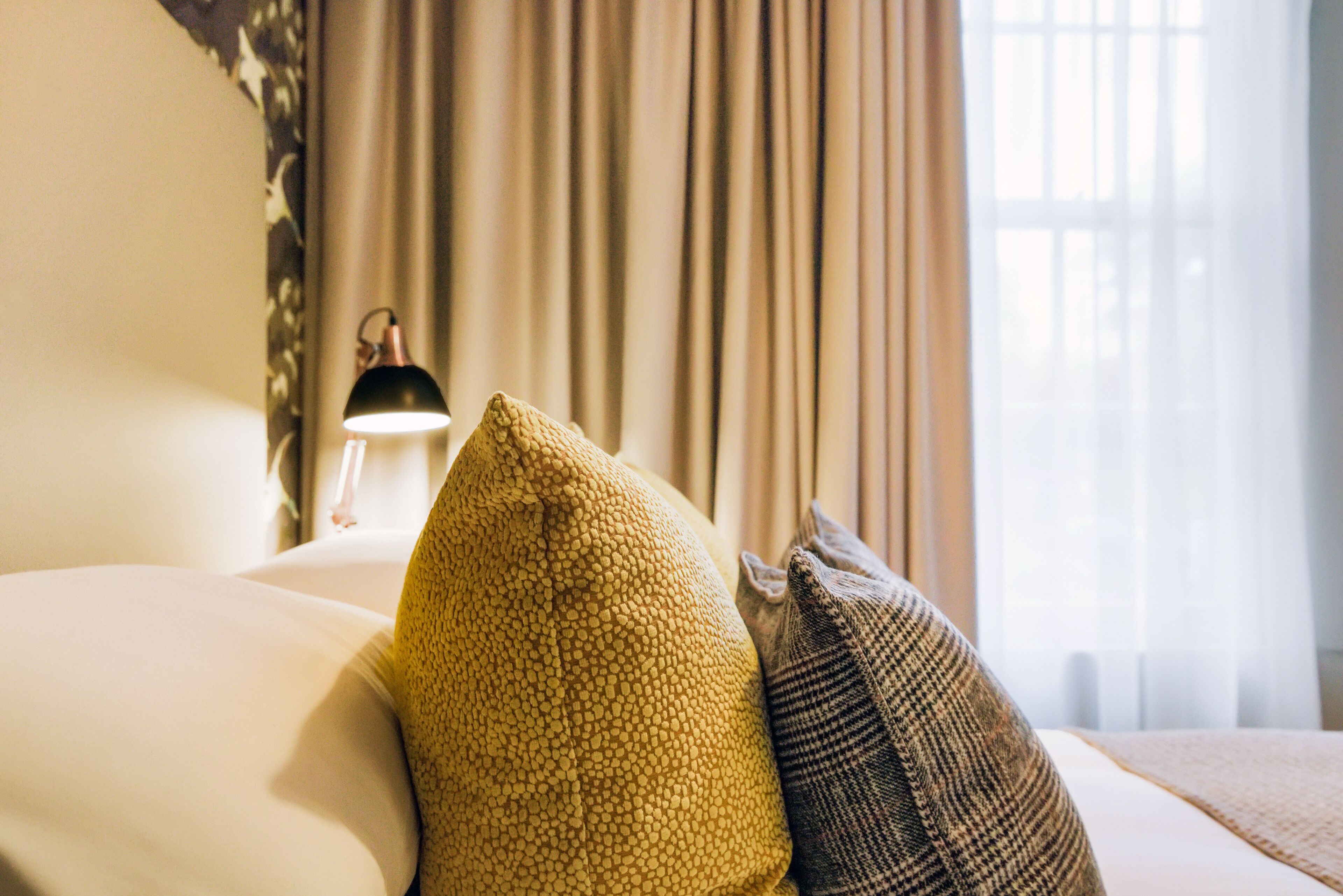 Una habitación de hotel con una cama, una lámpara y cortinas.