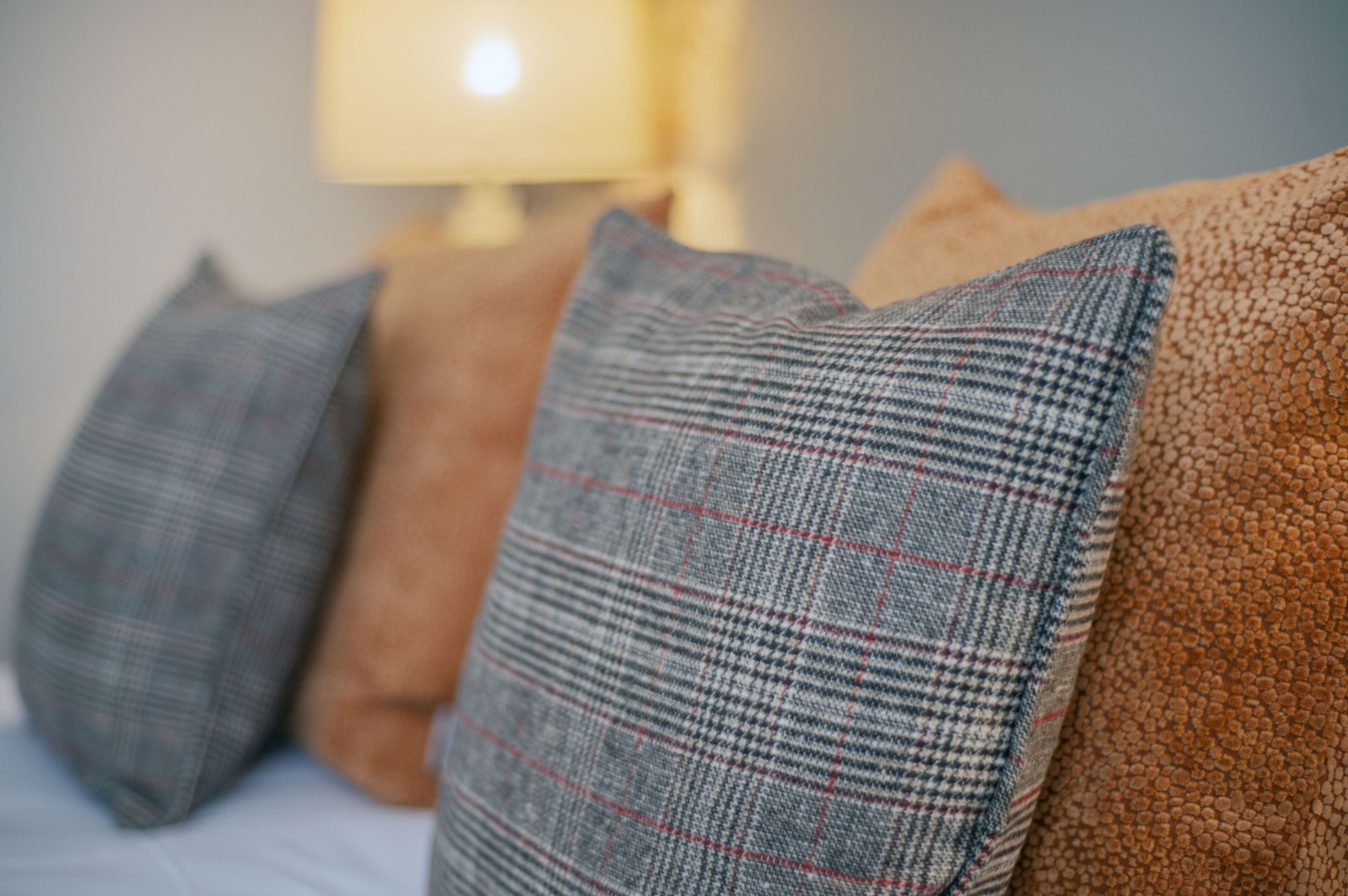 Um close-up de uma cama com várias almofadas em diferentes texturas e cores.