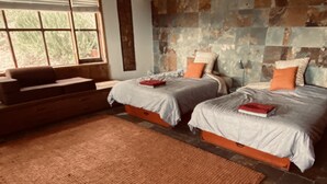 Una habitación con dos camas, un sofá y un ventanal grande.
