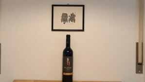 Una lámpara colgante sobre una mesa con un cuadro enmarcado y una botella de vino.