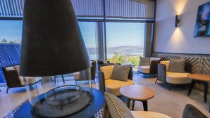 Un salon moderne doté d’une cheminée, de sièges confortables et de grandes fenêtres offrant une vue panoramique.