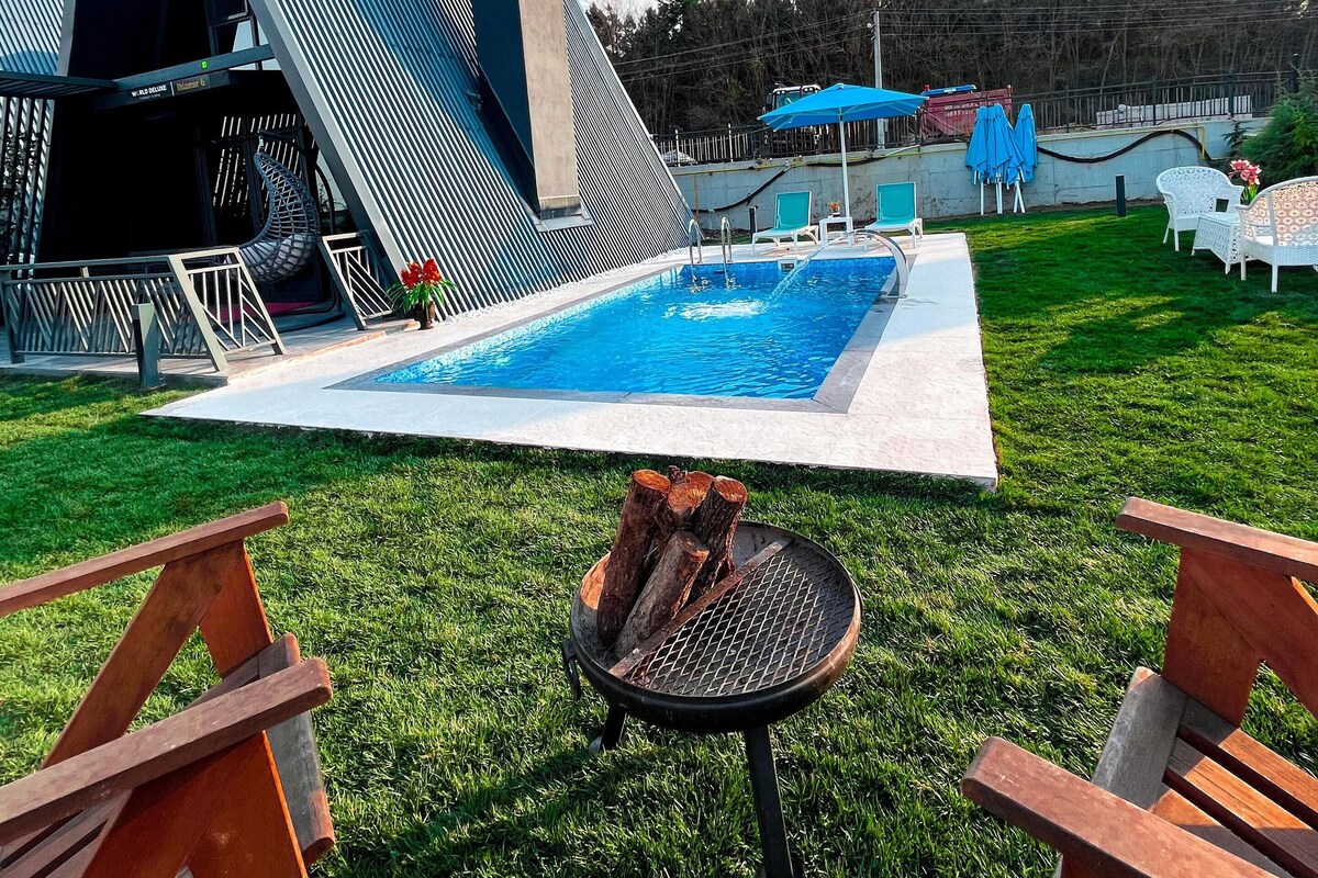 A modern outdoor pool area with a unique architectural structure, a fire pit, and outdoor seating.