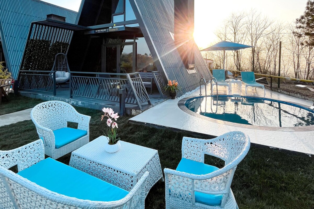 A modern building with a unique angular design, a swimming pool, and outdoor seating with blue cushions.