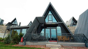 Un bâtiment moderne doté d’un toit triangulaire, de grandes fenêtres et d’une rambarde métallique à l’avant.