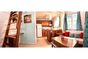 Uma cozinha compacta com armários de madeira, geladeira e área de refeições com mesa e cadeiras.