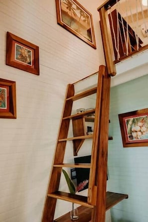 Eine Holzleiterregal an einer weißen Wand mit gerahmten Bildern.