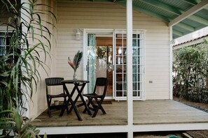 Eine überdachte Veranda mit Tisch und Stühlen, umgeben von Pflanzen.