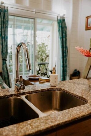 A kitchen with a stainless steel sink, a faucet, and a countertop.