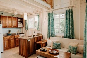 A cozy kitchen with wooden cabinets, a central island, and a dining area with a sofa and cushions.