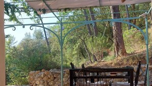 An outdoor patio with a table and chairs, a stone wall, and a pergola with hanging lights. - Magnifique Villa Provençale Entre Golfe de St Tropez et Verdon (Vidauban)