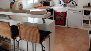 A modern kitchen with a central island, bar stools, a dishwasher, and artwork on the walls. - Magnifique Villa Provençale Entre Golfe de St Tropez et Verdon (Vidauban)