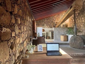 Une pièce aux murs de pierre, avec un bureau en bois, un ordinateur portable et une cheminée.
