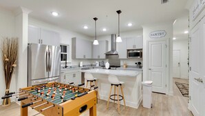 A modern kitchen with a foosball table, stainless steel appliances, and a pantry sign. - Comfy Cottage (Mobile)