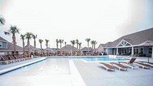 A large outdoor swimming pool with lounge chairs and palm trees. - Comfy Cottage (Mobile)