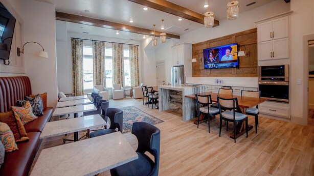 A modern kitchen with a TV, wooden cabinets, and a marble countertop. - Comfy Cottage (Mobile)