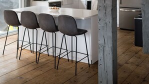 Une cuisine moderne dotée d’un îlot central, de tabourets de bar et d’un réfrigérateur en acier inoxydable.