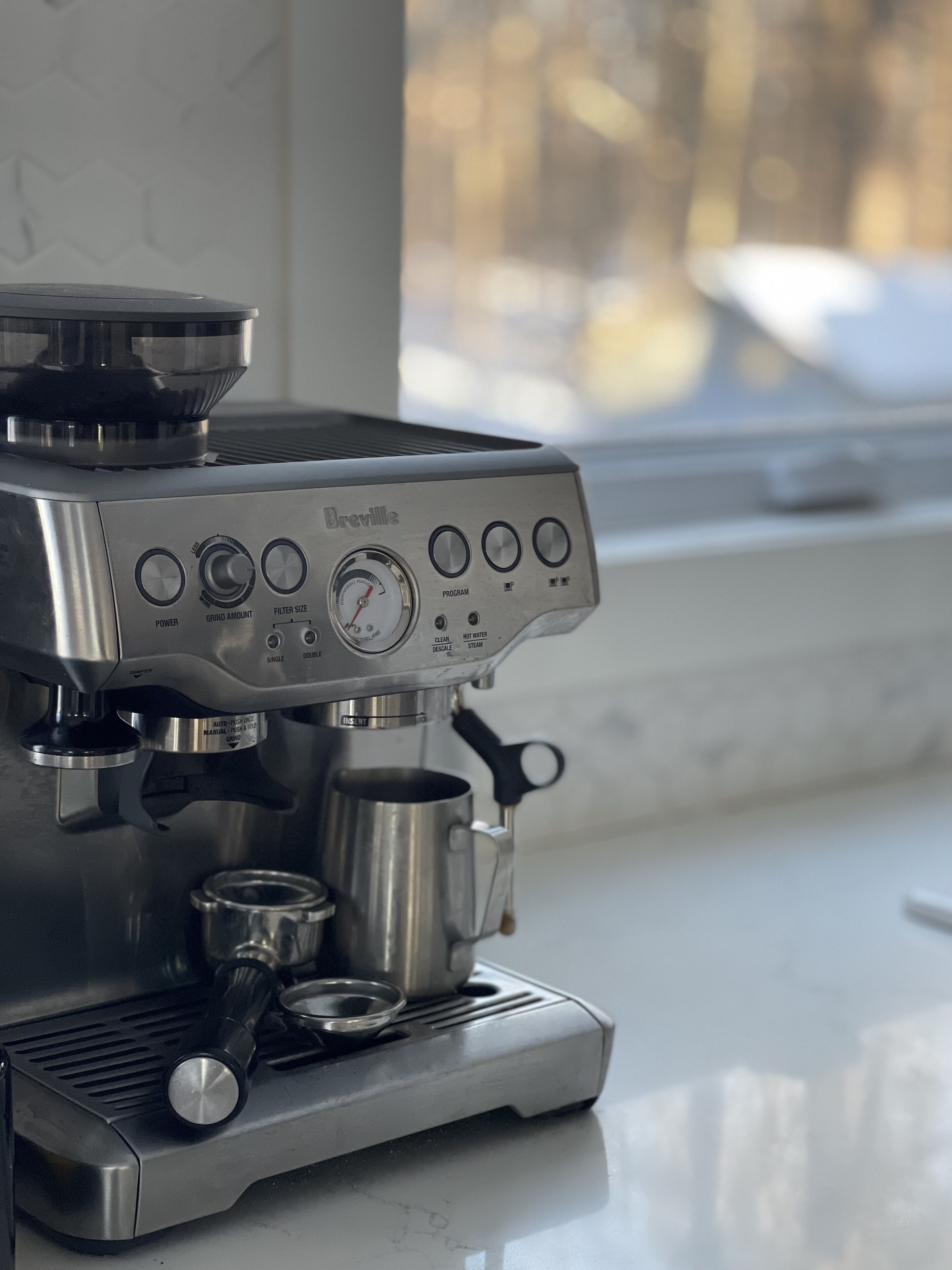 Eine Espressomaschine von Breville mit Digitalanzeige, Brühgruppe und einem Milchaufschäumkännchen.