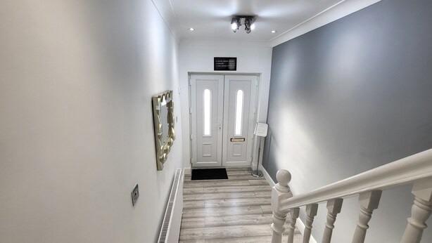 A hallway with a white door, a radiator, and a staircase with white balusters. - Top Luxury 2 bed Apartment - London (London)