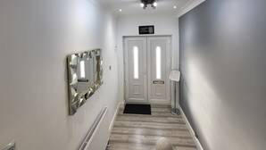 A hallway with a white door, a mirror, and a radiator. - Top Luxury 2 bed Apartment - London (London)