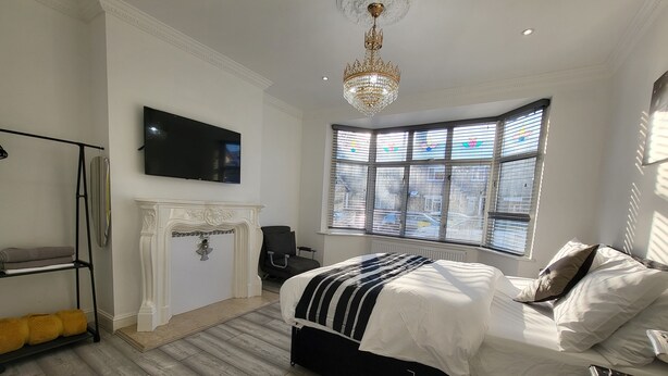 Une chambre moderne avec un grand lit, une cheminée, un téléviseur et un lustre.