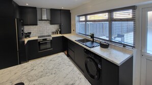 Une cuisine moderne avec des meubles de couleur noire, un plan de travail en marbre et un lave-vaisselle encastré.