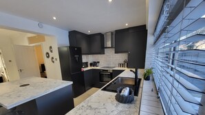Une cuisine moderne avec des meubles noirs, un îlot en marbre et un four encastré.