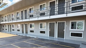 A multi-story motel with individual rooms, a parking lot, and a balcony on the upper floor. - Bostonian Inn (New Boston)