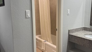 A bathroom with a shower, a bathtub, and a granite countertop sink. - Bostonian Inn (New Boston)