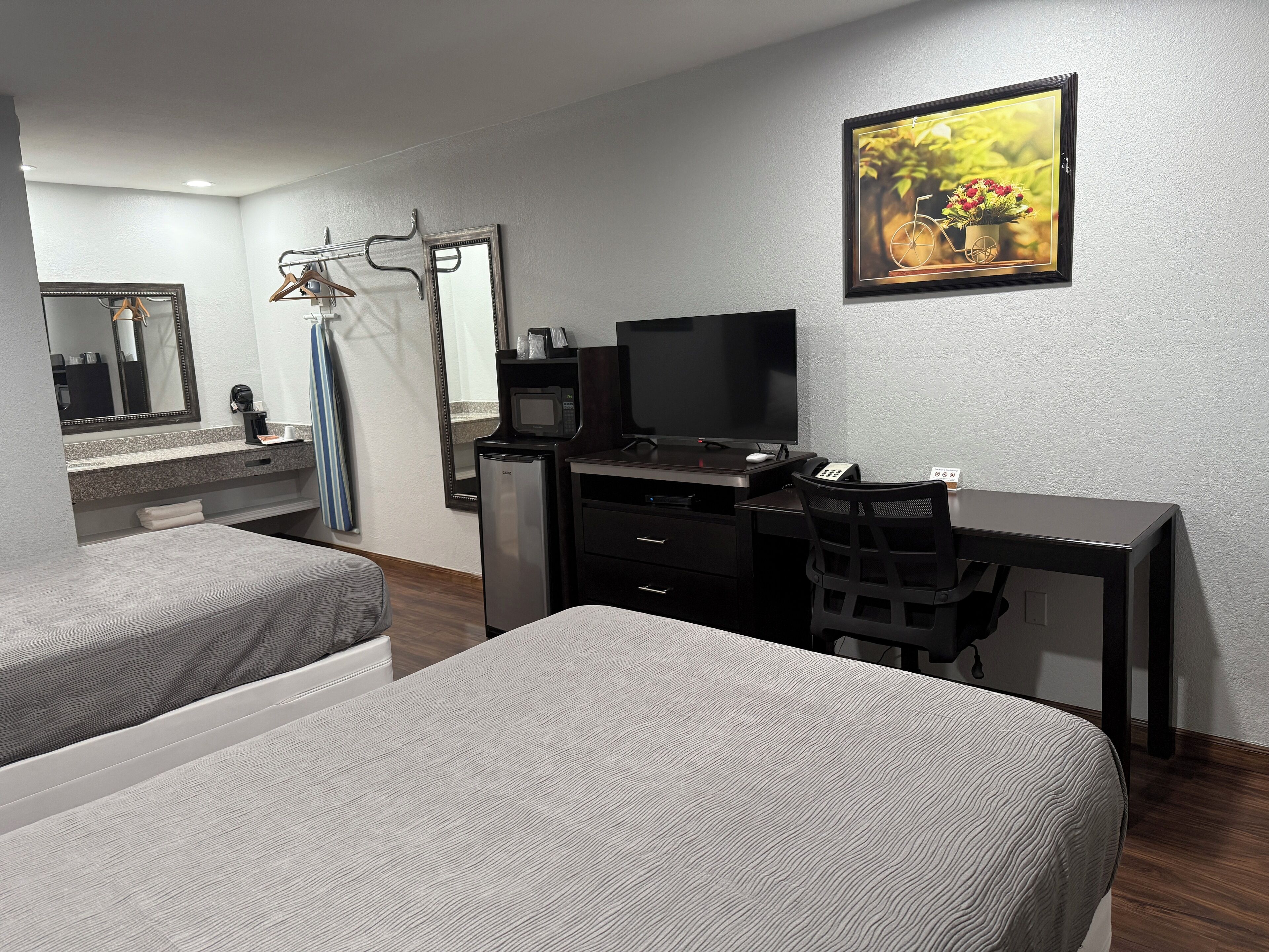 Une chambre d’hôtel avec deux lits, un bureau, une télévision et un miroir.
