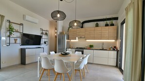 A modern kitchen with white cabinetry, a dining table with white chairs, and pendant lighting. - VILLA RARIKI, POOL AND RELAX (Scicli)