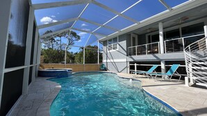 A swimming pool with clear water, surrounded by a covered area with lounge chairs and a staircase leading to an upper level. - Private heated pool & spa home. Close to beach! (Naples)