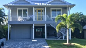 A two-story house with a balcony, a garage, and a well-maintained lawn. - Private heated pool & spa home. Close to beach! (Naples)