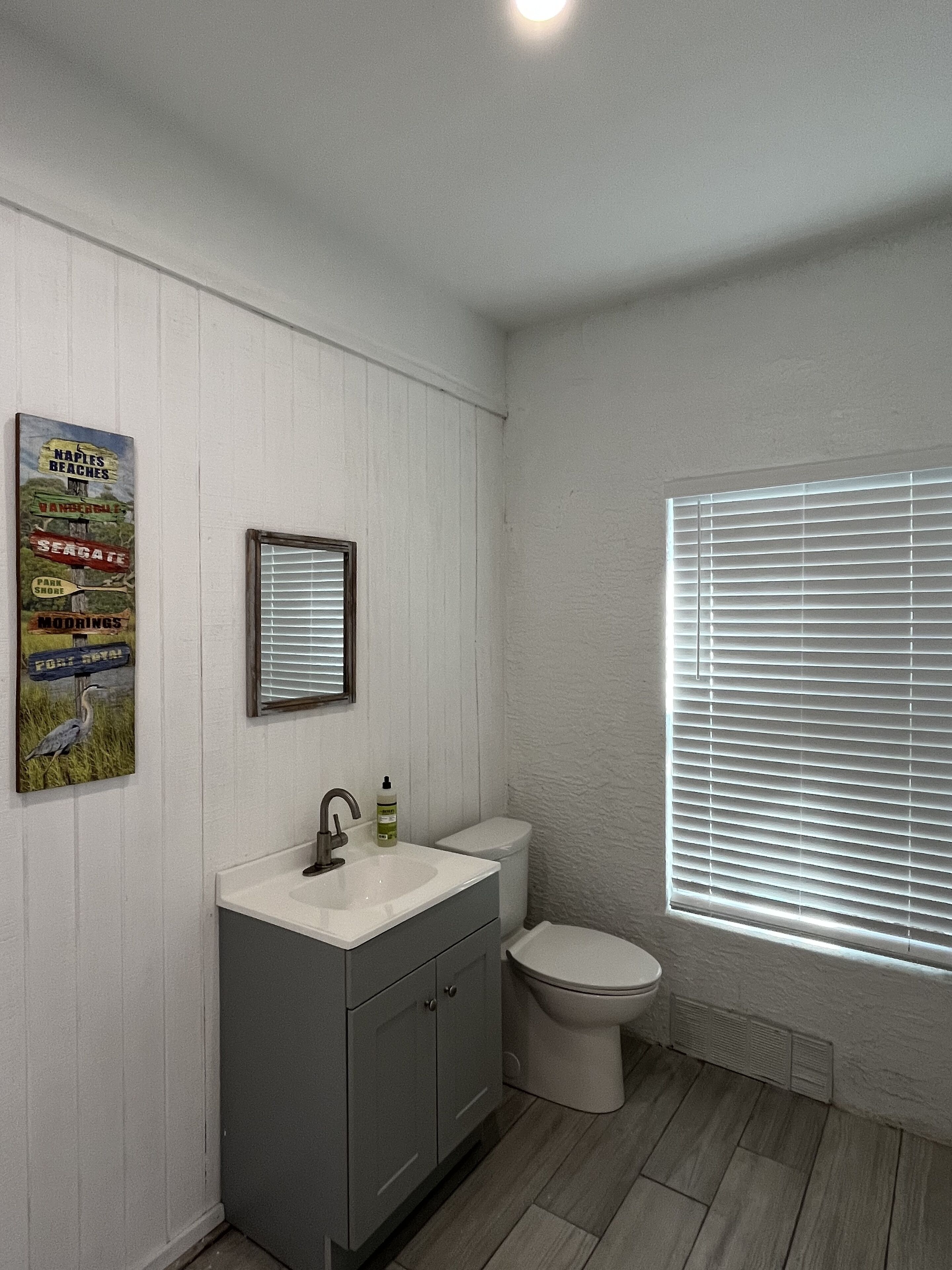 A bathroom with a white sink, a toilet, and a window with blinds.